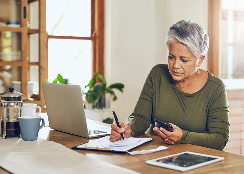 Shot of a woman going through financial paperwork at home